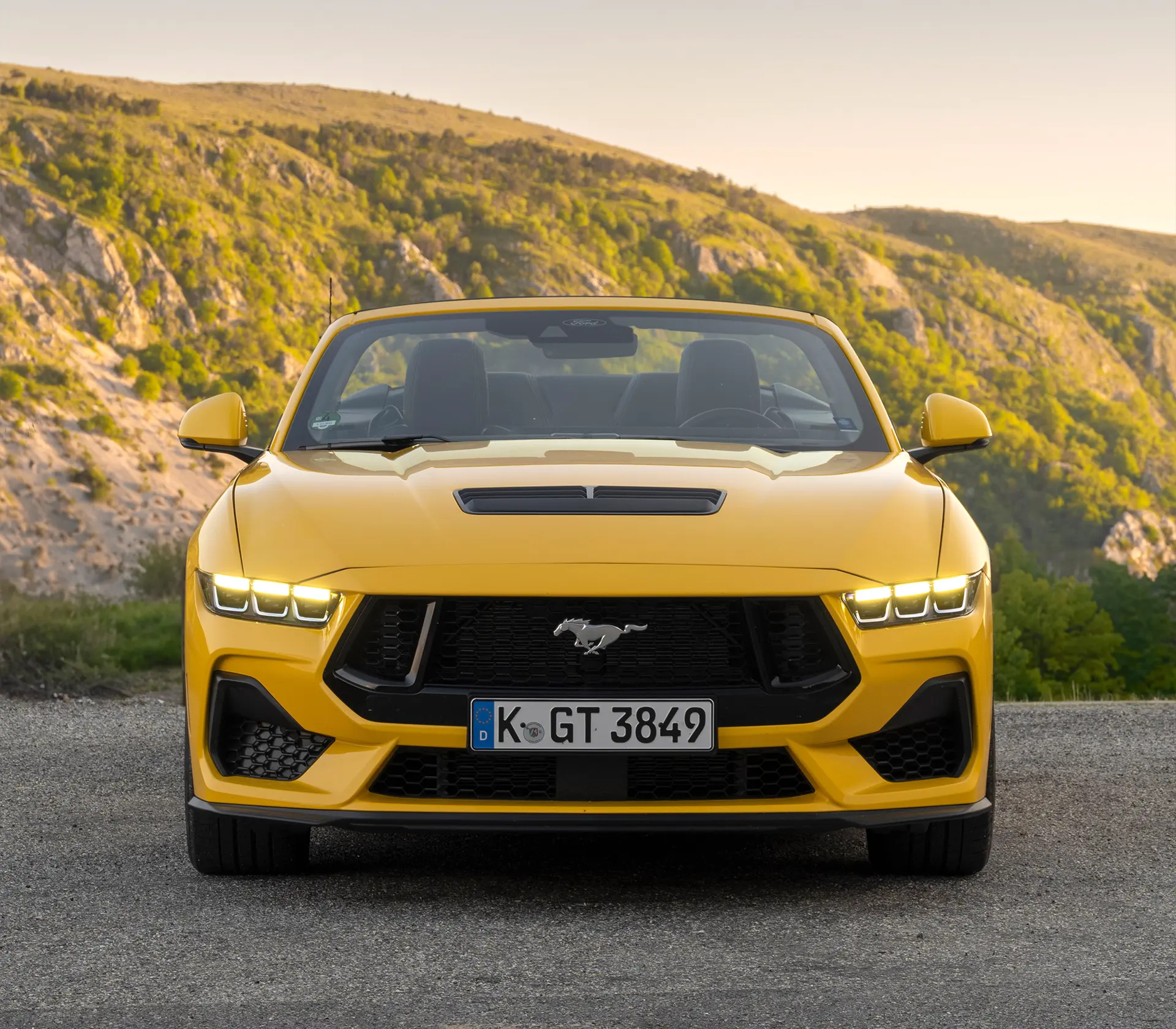 Frontansicht auf gelben Ford Mustang mit bergen im Hintergrund