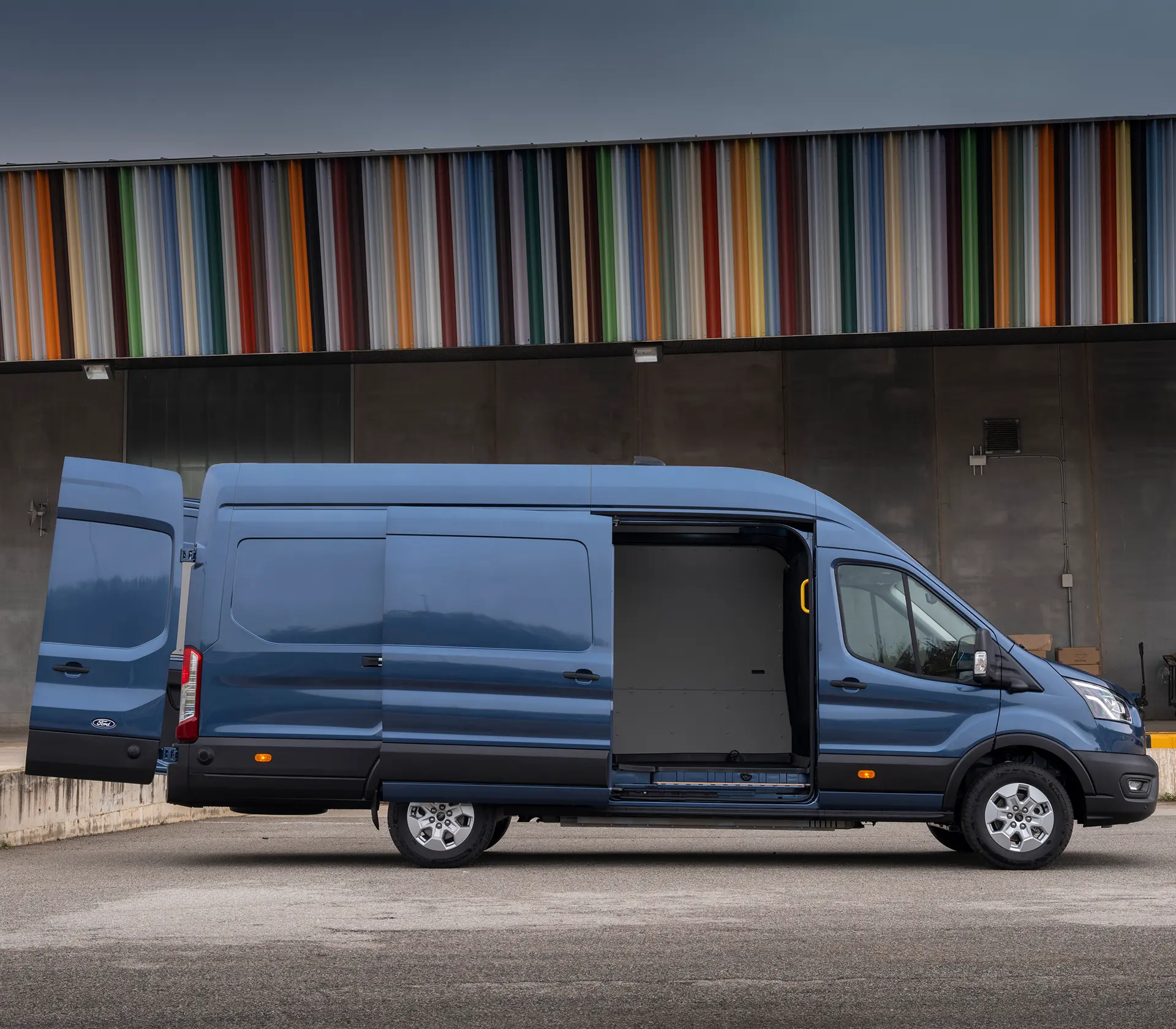 blauer E-Transit in seitlicher Ansicht mit offener Schiebetür und offenen Türen hinten