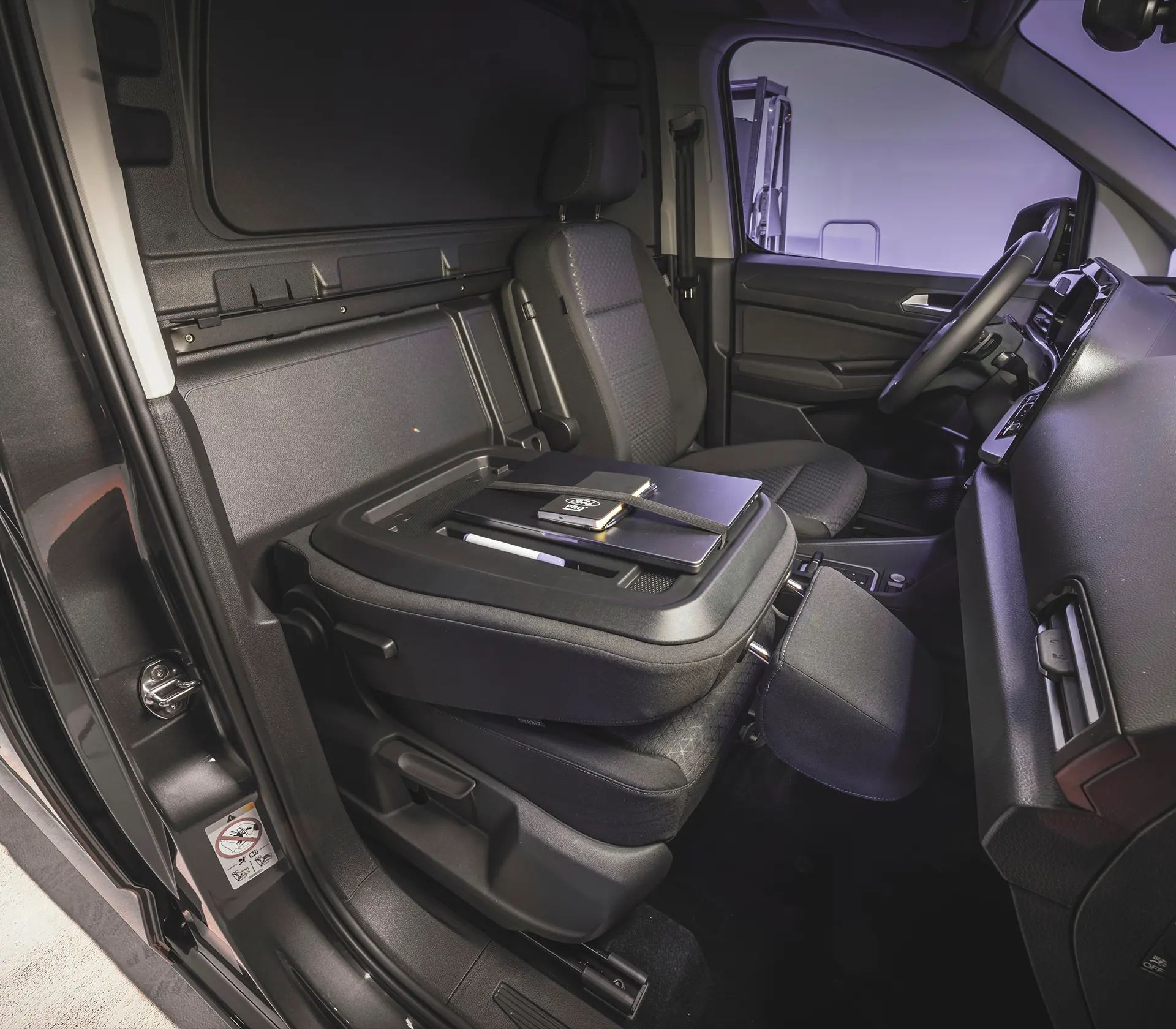 umgeklappter Sitz i Vorderraum des Transit-Connect, welcher zur Arbeitsfläche mit Laptop und Notizblock umfunktioniert wurde