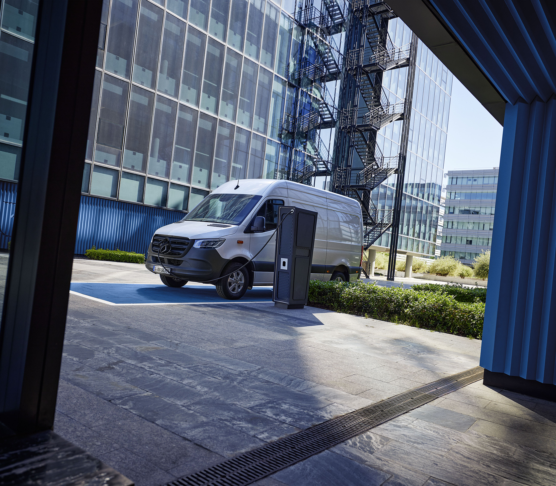 Mercedes-Benz e-Sprinter am Laden mit einem Glasgebäude im Hintergrund