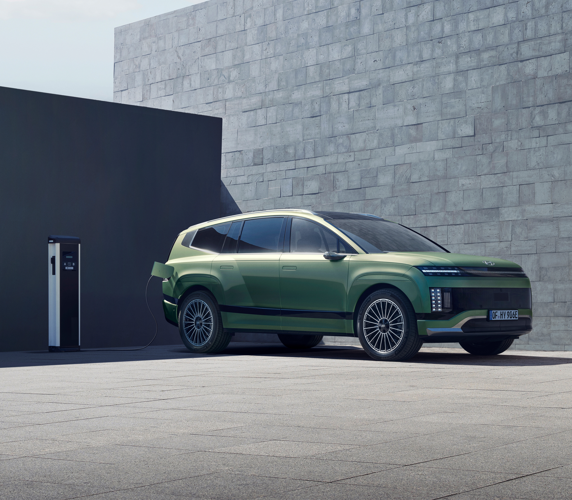 Hyundai IONIQ 9 in Grün beim Ladevorgang vor einer schlichten grauen Wand
