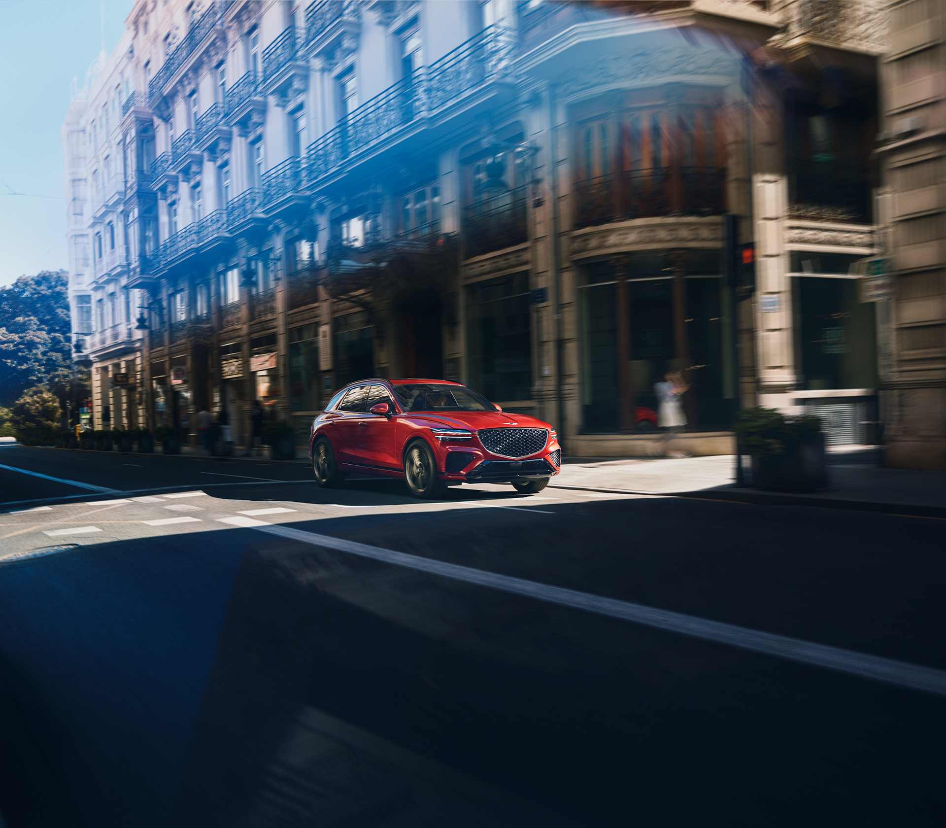 Genesis GV 70 in rot fährt auf der Straße mit einem Gebäude im Hintergrund