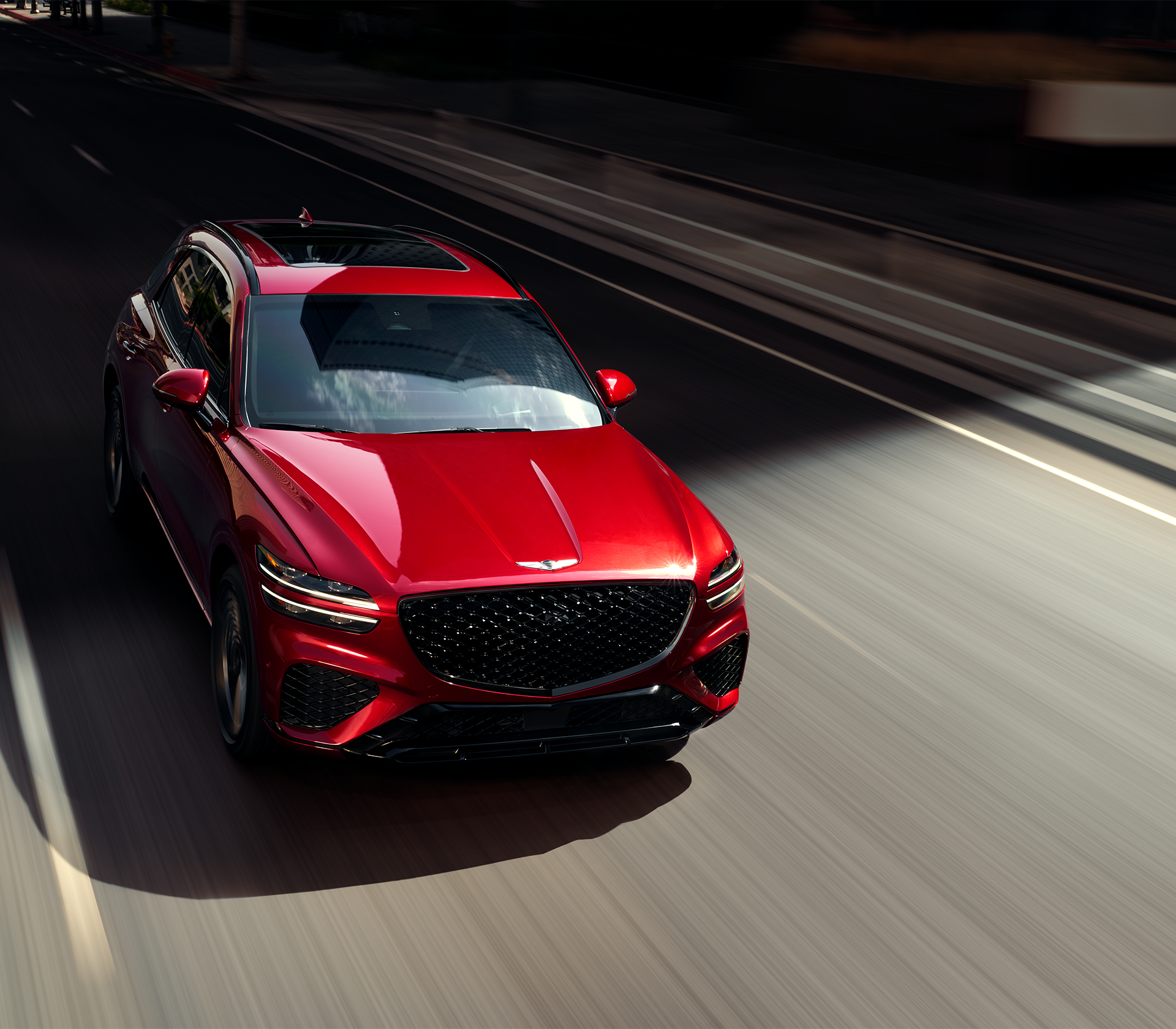 Genesis GV 70 in rot Ansicht von vorne und oben während das Auto auf der Straße fährt