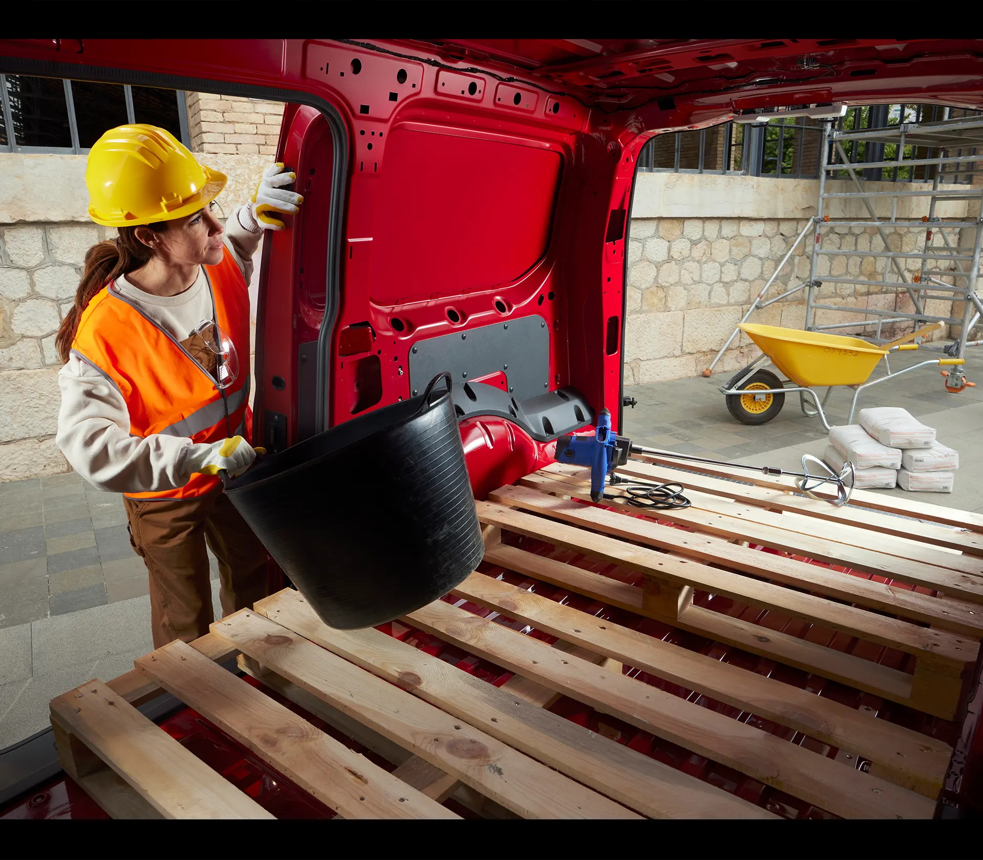 Frau legt einen Eimer in den Laderaum des Transit-Connect in dem sich eine Palette befindet