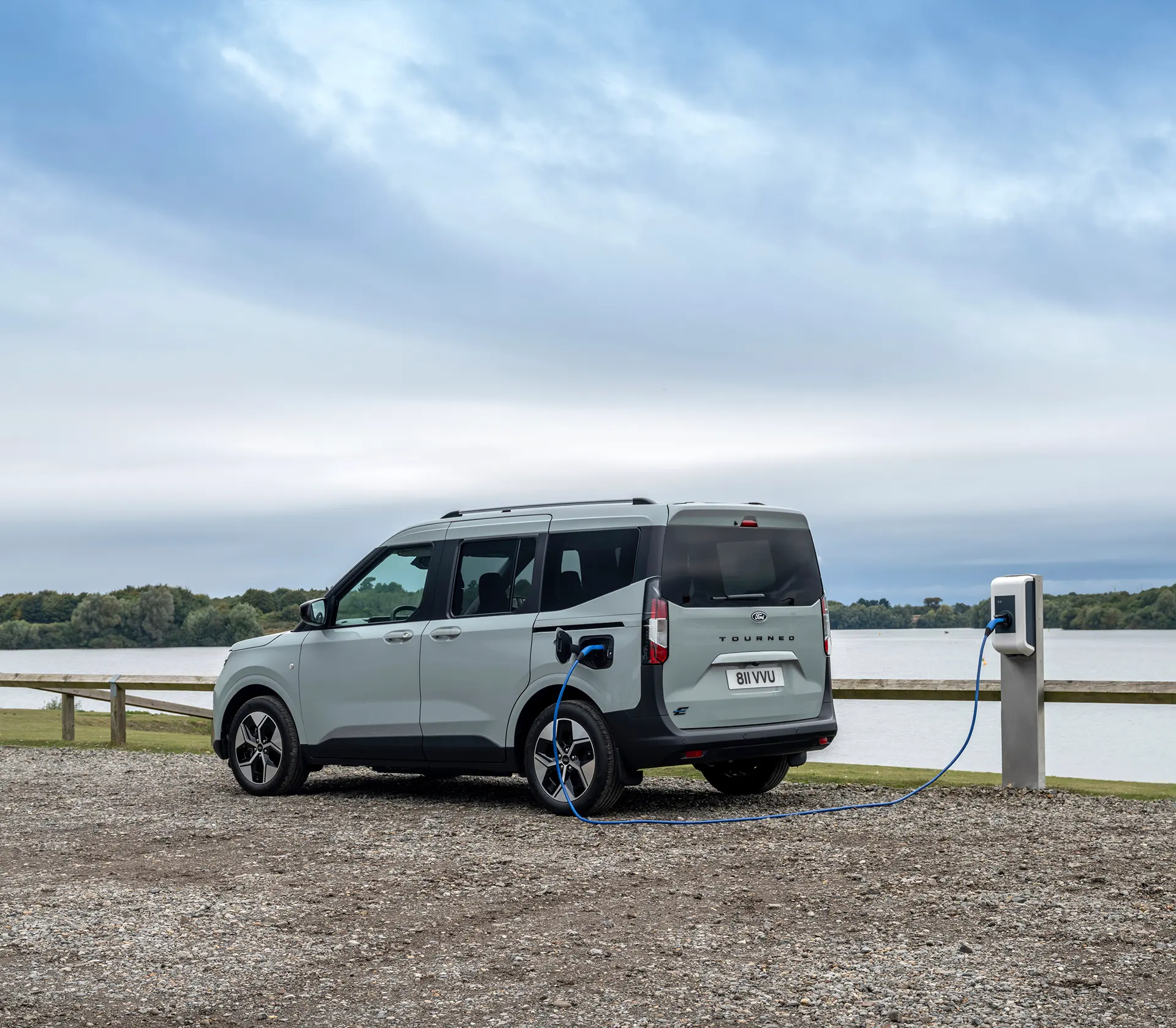 E-Tourneo Courier läd an der Ladesäule mit See im Hintergrund