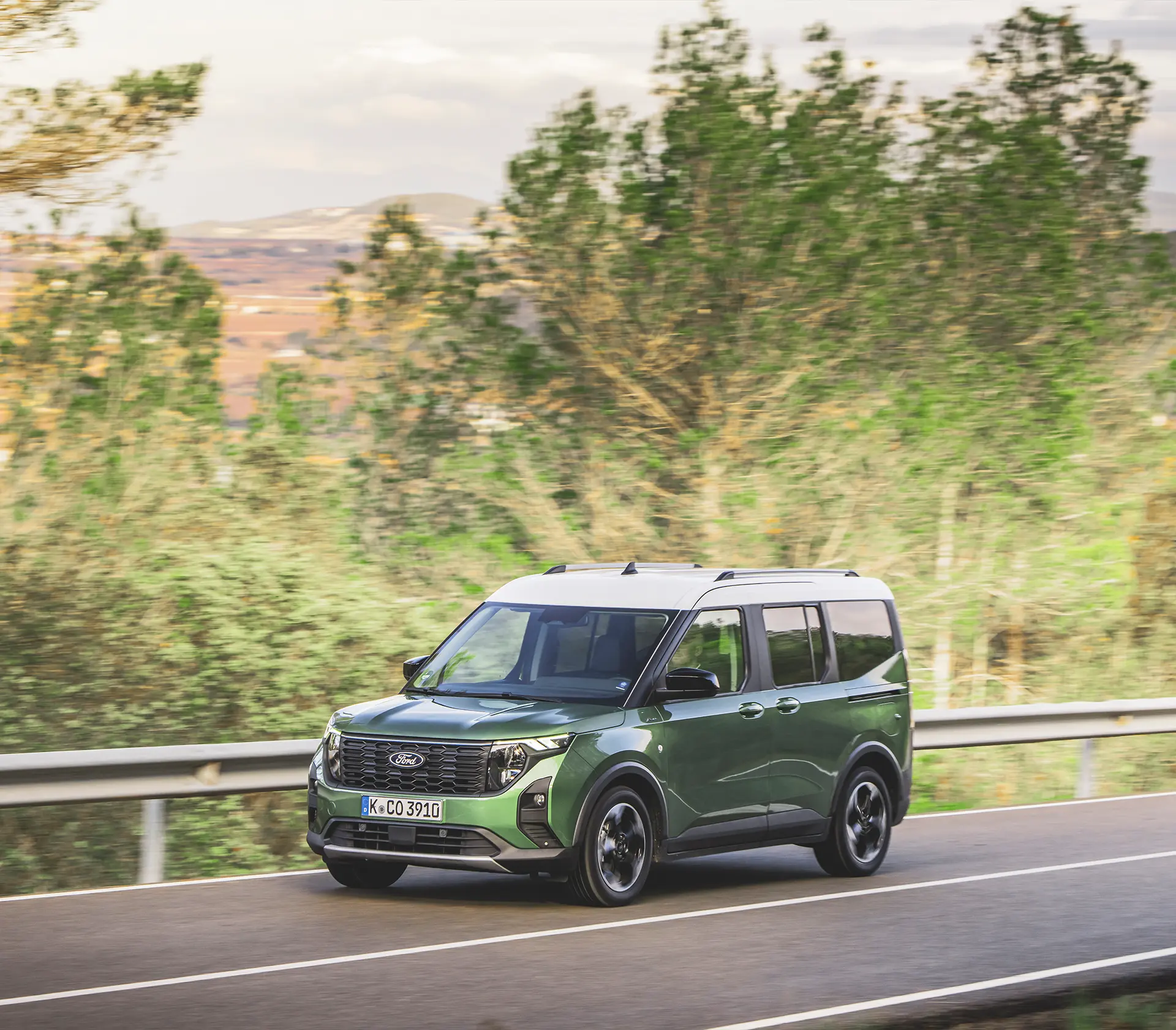 die Frontansicht auf einen grünen Tourneo Courier der auf der Straße fährt