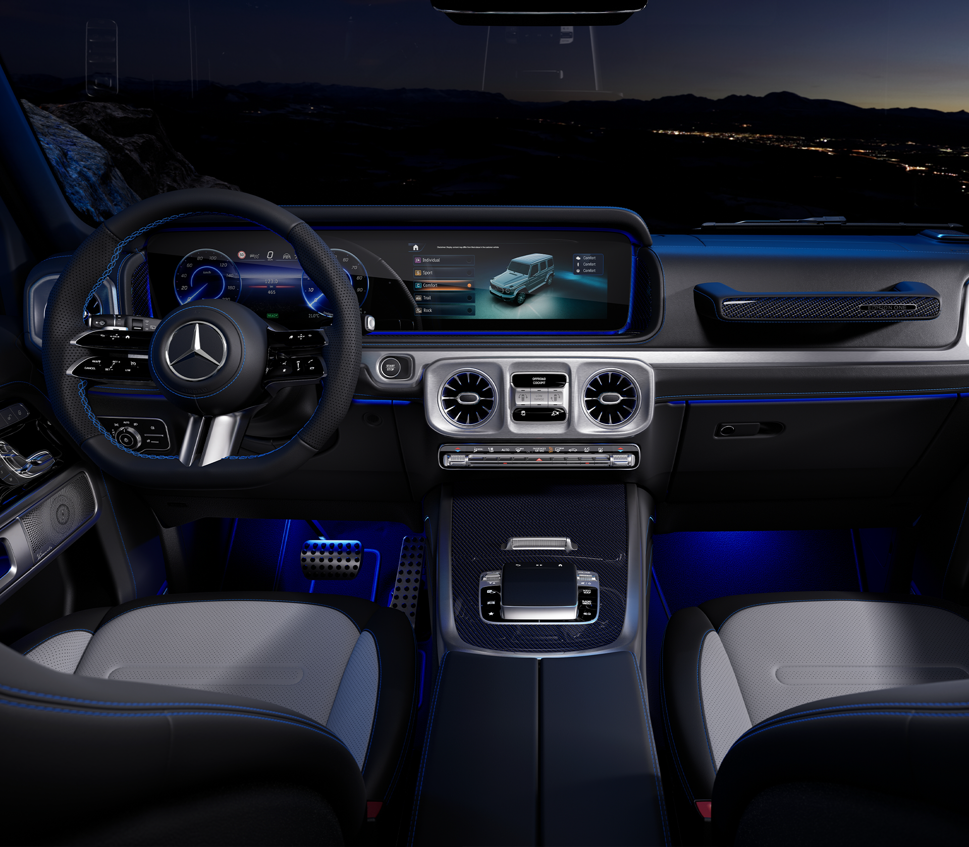 Mercedes-Benz G-Klaasse elektrisch Innenraum mit den beiden Vordersitzen, dem Lenkrad und dem Bildschirm und dem Griff auf der BEifahrerseite