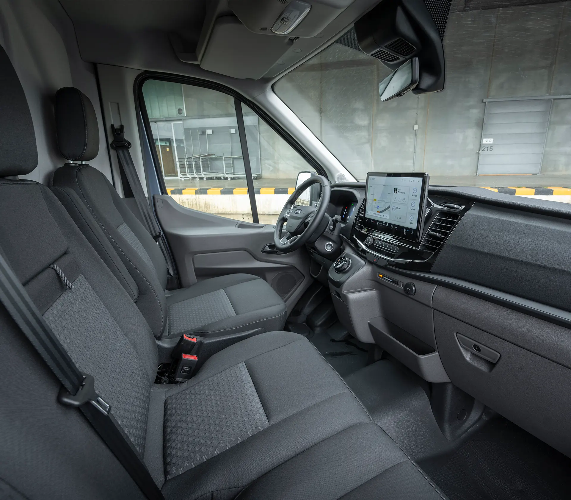 graue Sitze des vorderen Innenraums eines E-Transit mit Sicht auf das Interieur