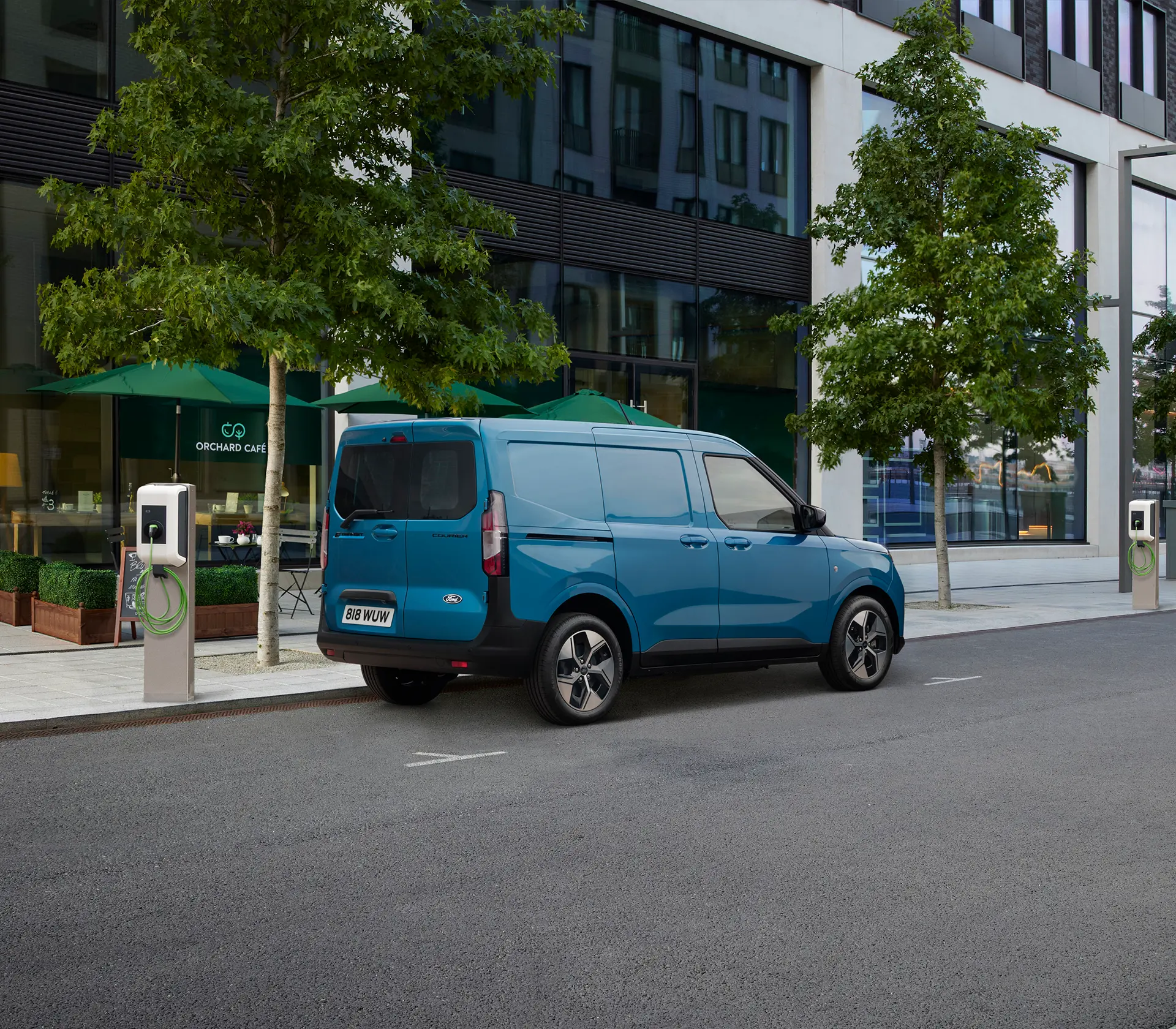 blauer E-Transit Courier auf der Straße neben einer Ladesäule