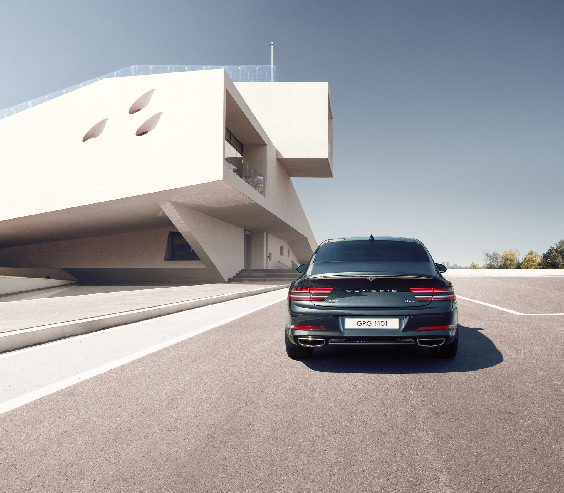 Genesis g80 Heckansicht fährt auf der Straße, danaben ist ein modernes Gebäude