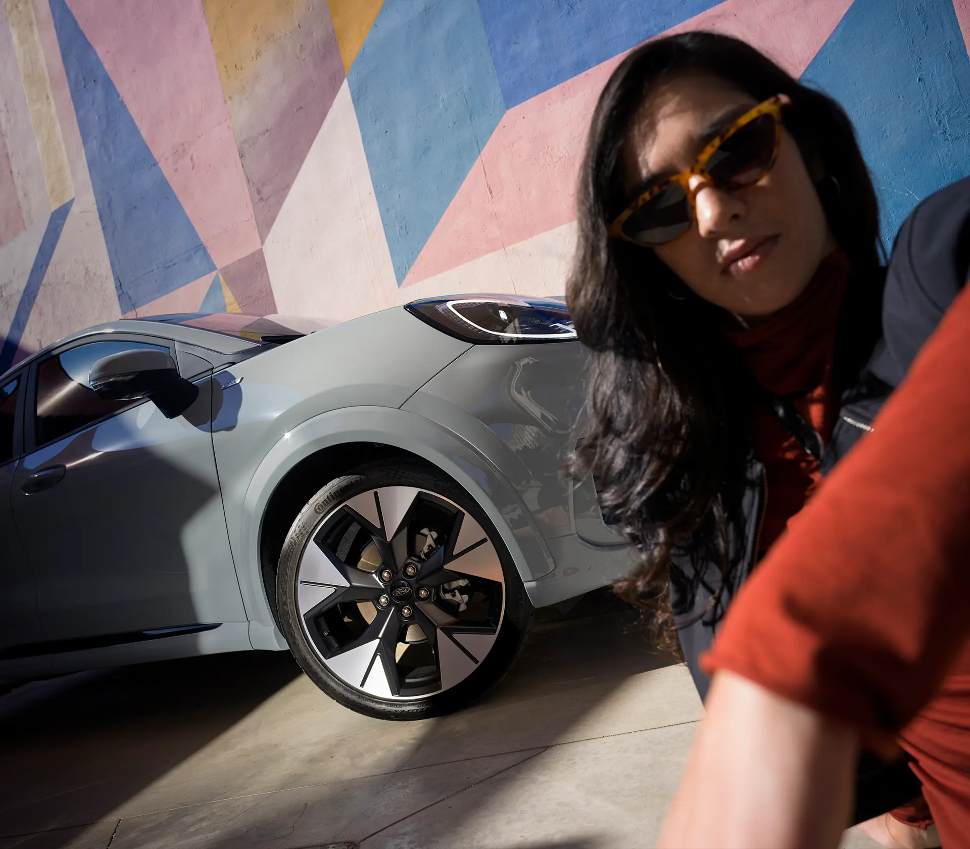 Frau sitzt unten rechts im Bild neben den Rädern/Reifen des Puma