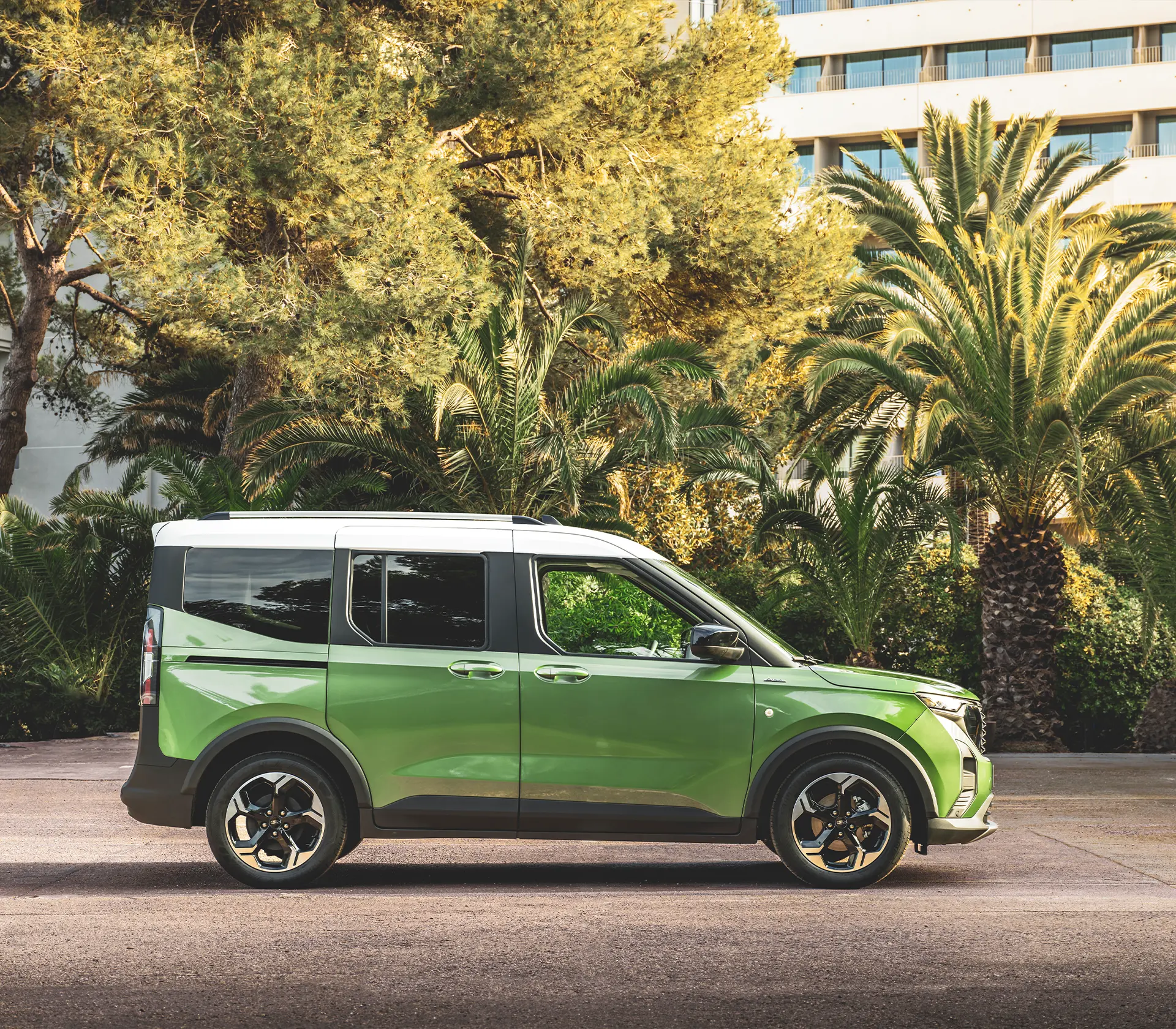 ein grüner Tourneo Courier im Stand von der Seite mit Plamen im Hintergrund