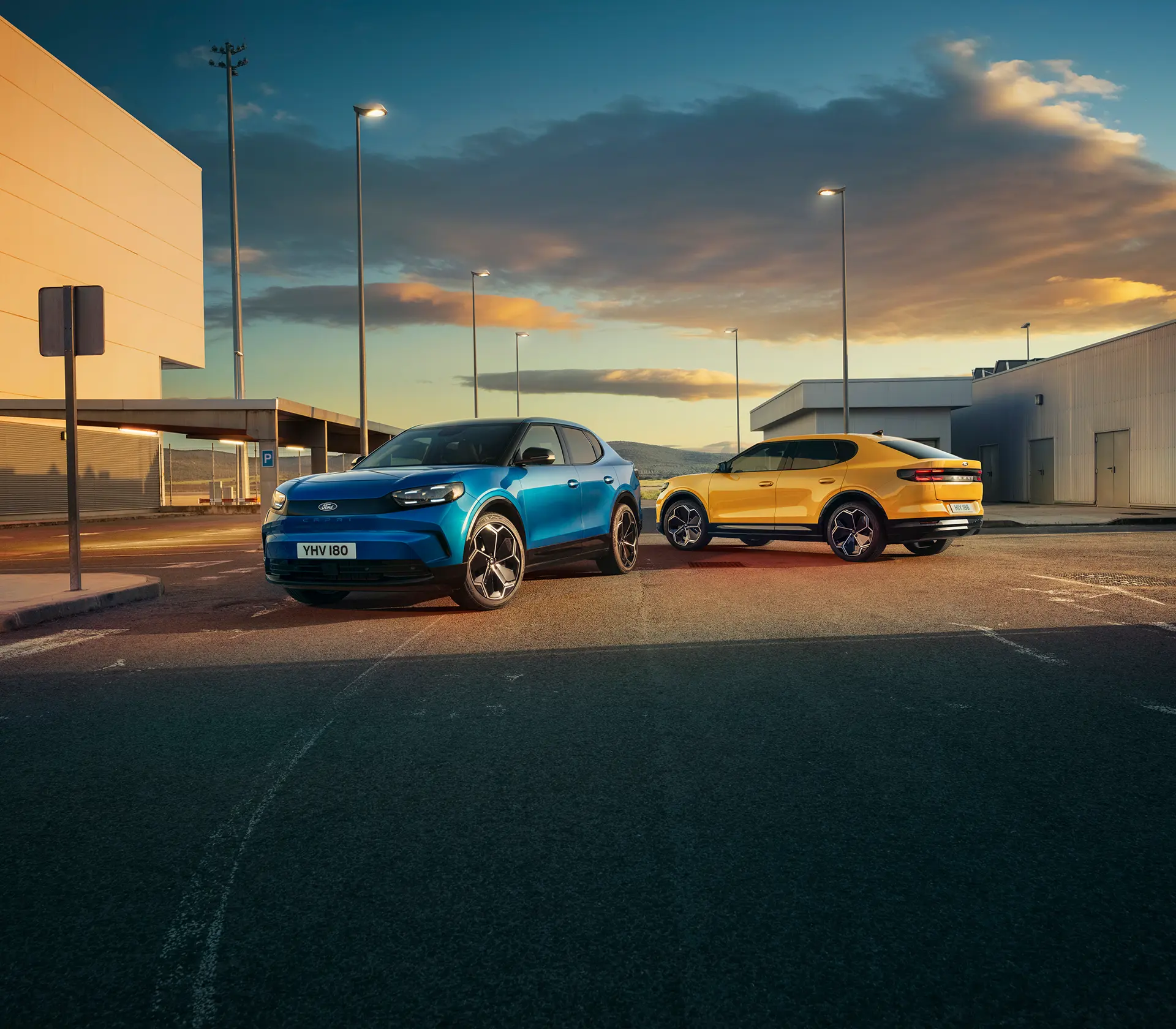 ein Blauer und ein gelber Capri auf einem Parkplatz mit Wolken und Sonne im Hintergrund