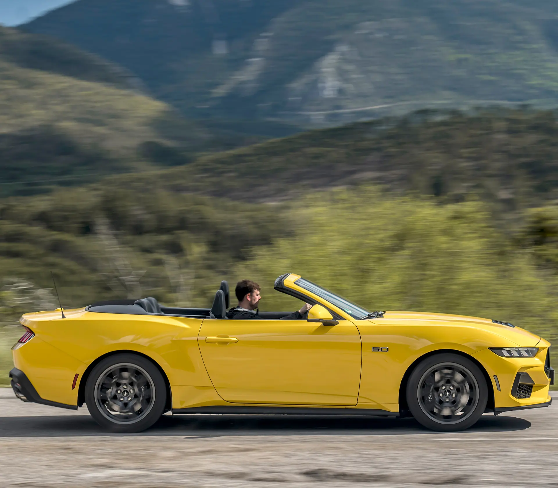 Seitenansicht auf einen gelben Ford Mustang mit geöffneten Cabrio Dach