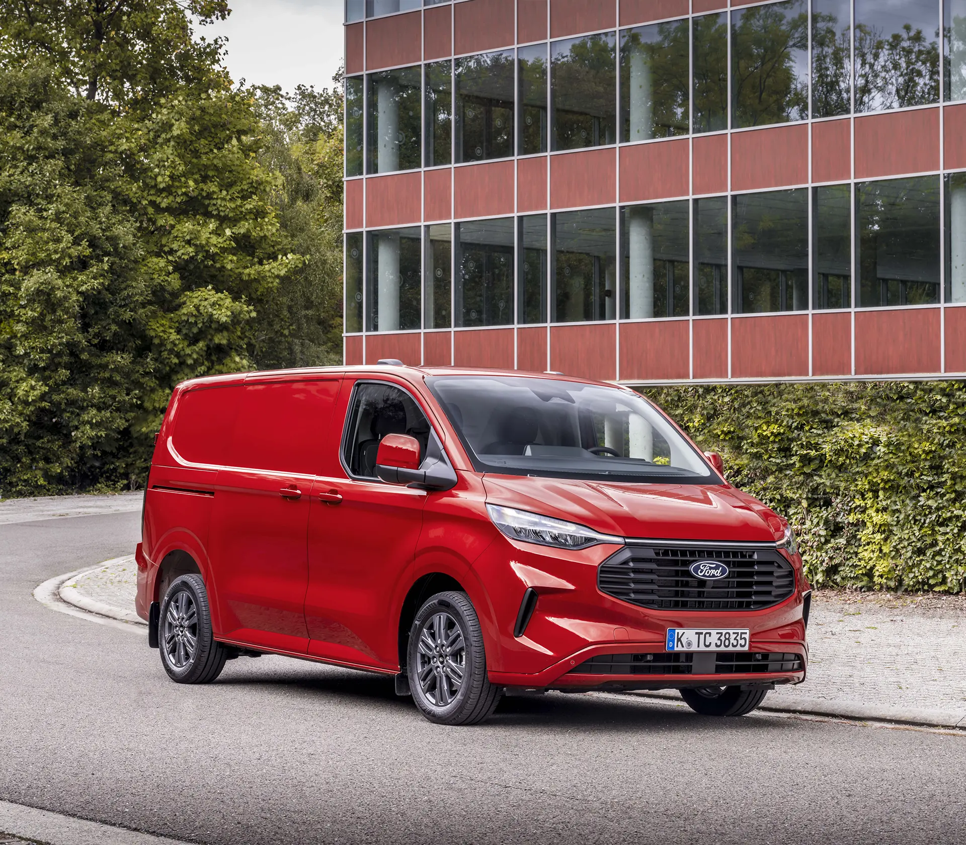 seitliche Ansicht auf roten Transit-Custom vor einem Glasgebäude