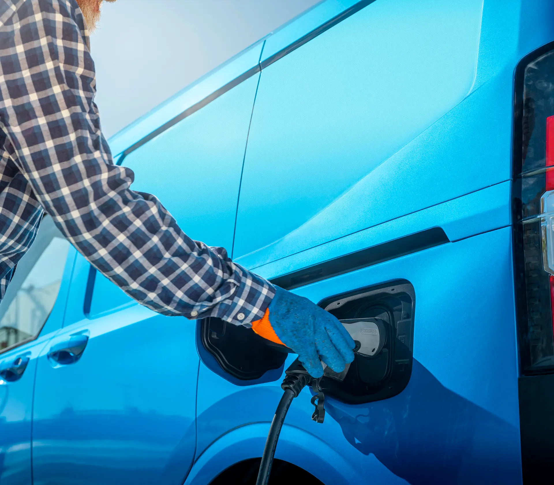 Mann läd blauen E-Transit Courier