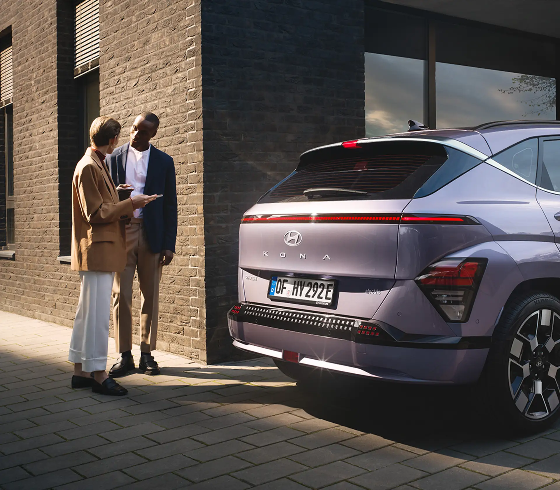 Mann und Frau stehen hinter einem Hyundai KONA