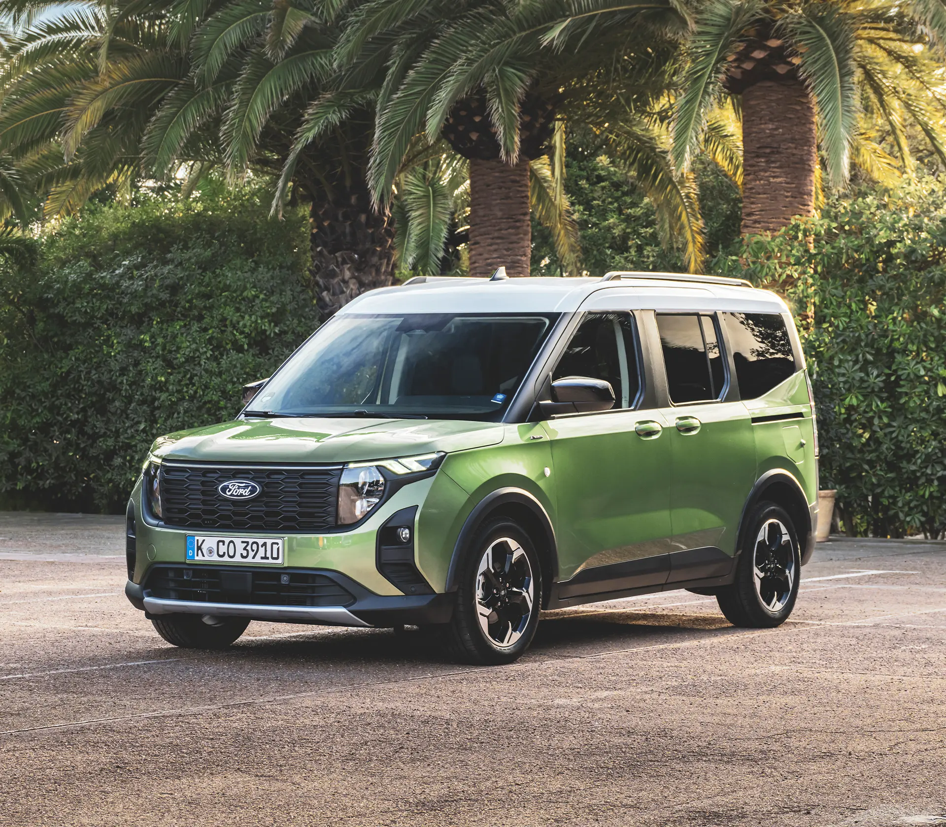 ein grüner Tourneo Courier im Stand von vorne mit Plamen im Hintergrund