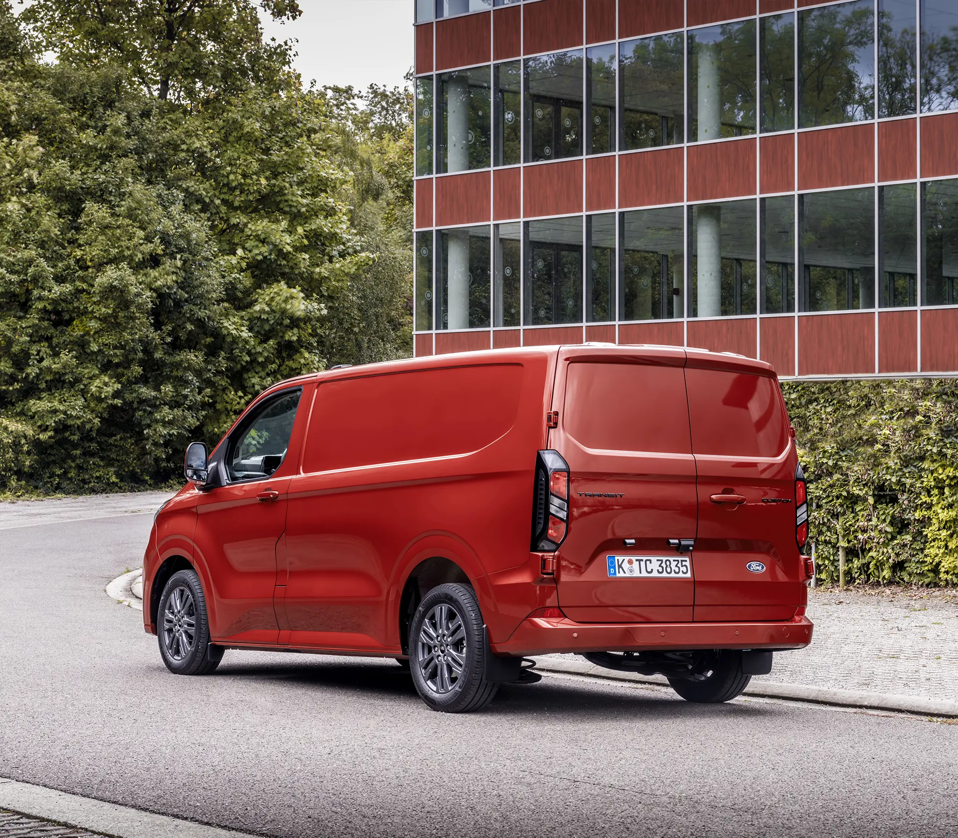 Heckansicht auf roten Transit-Custom vor einem Glasgebäude