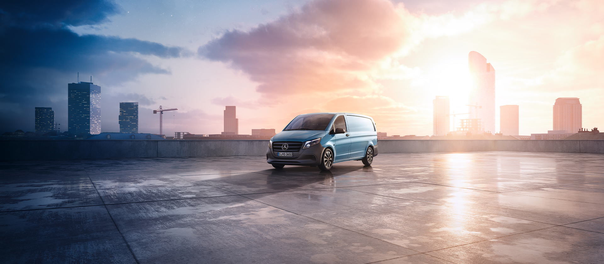 „Blauer Mercedes-Benz Vito auf einem Dachparkplatz mit Blick auf die Stadt bei Sonnenuntergang.“