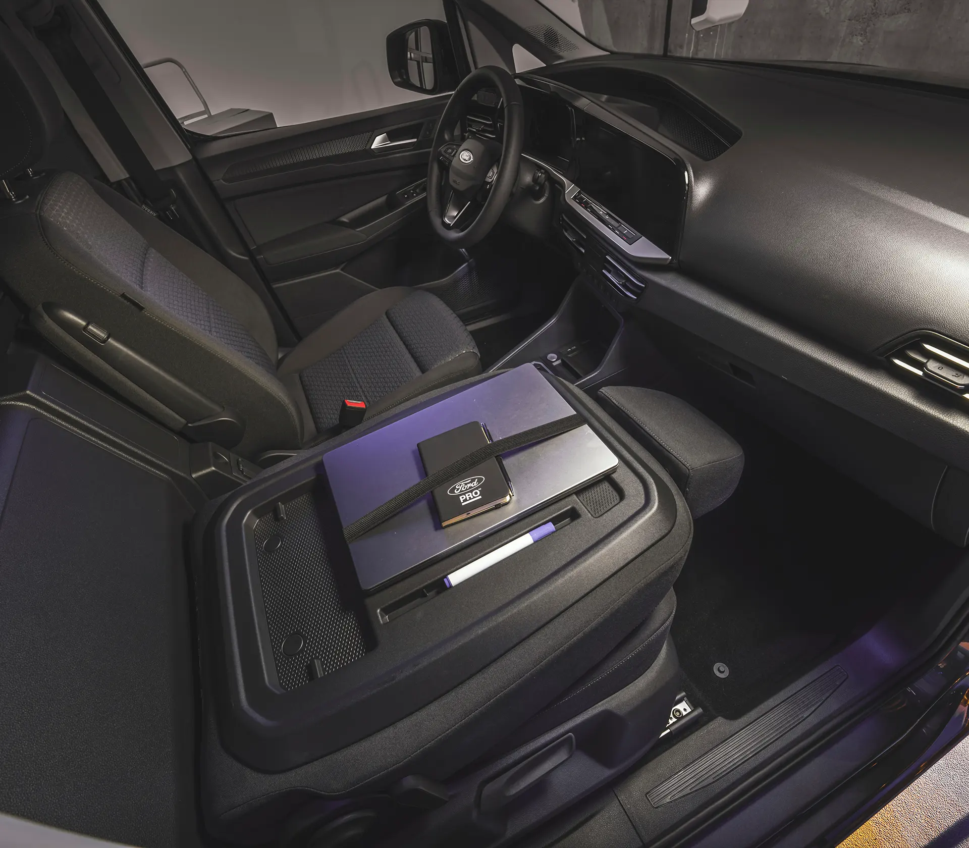 umgeklappter Sitz i Vorderraum des Transit-Connect, welcher zur Arbeitsfläche mit Laptop und Notizblock umfunktioniert wurde