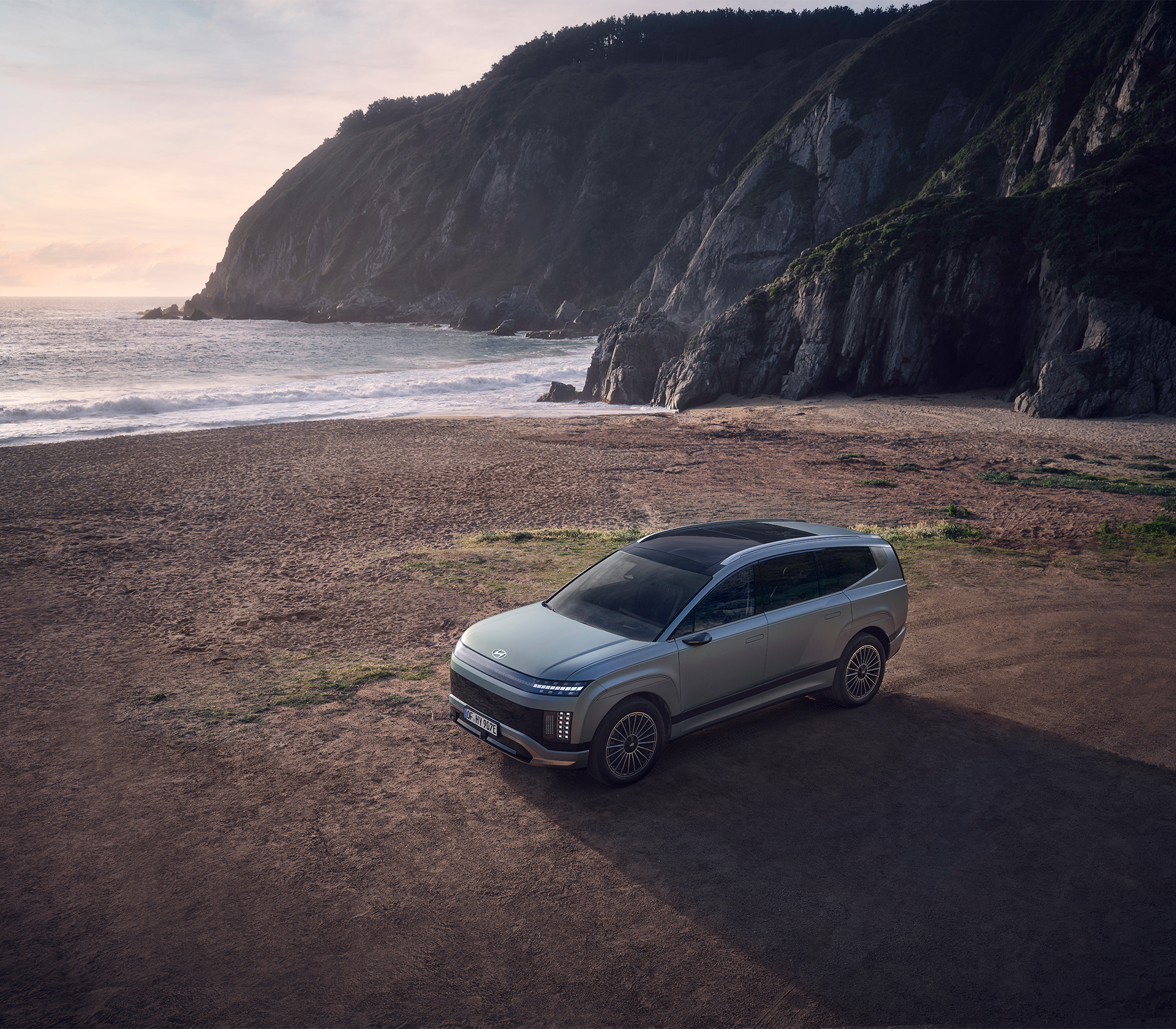 Hyundai IONIQ 9 von oben an einem Strand mit Felsen und dem Meer im Hintergrund