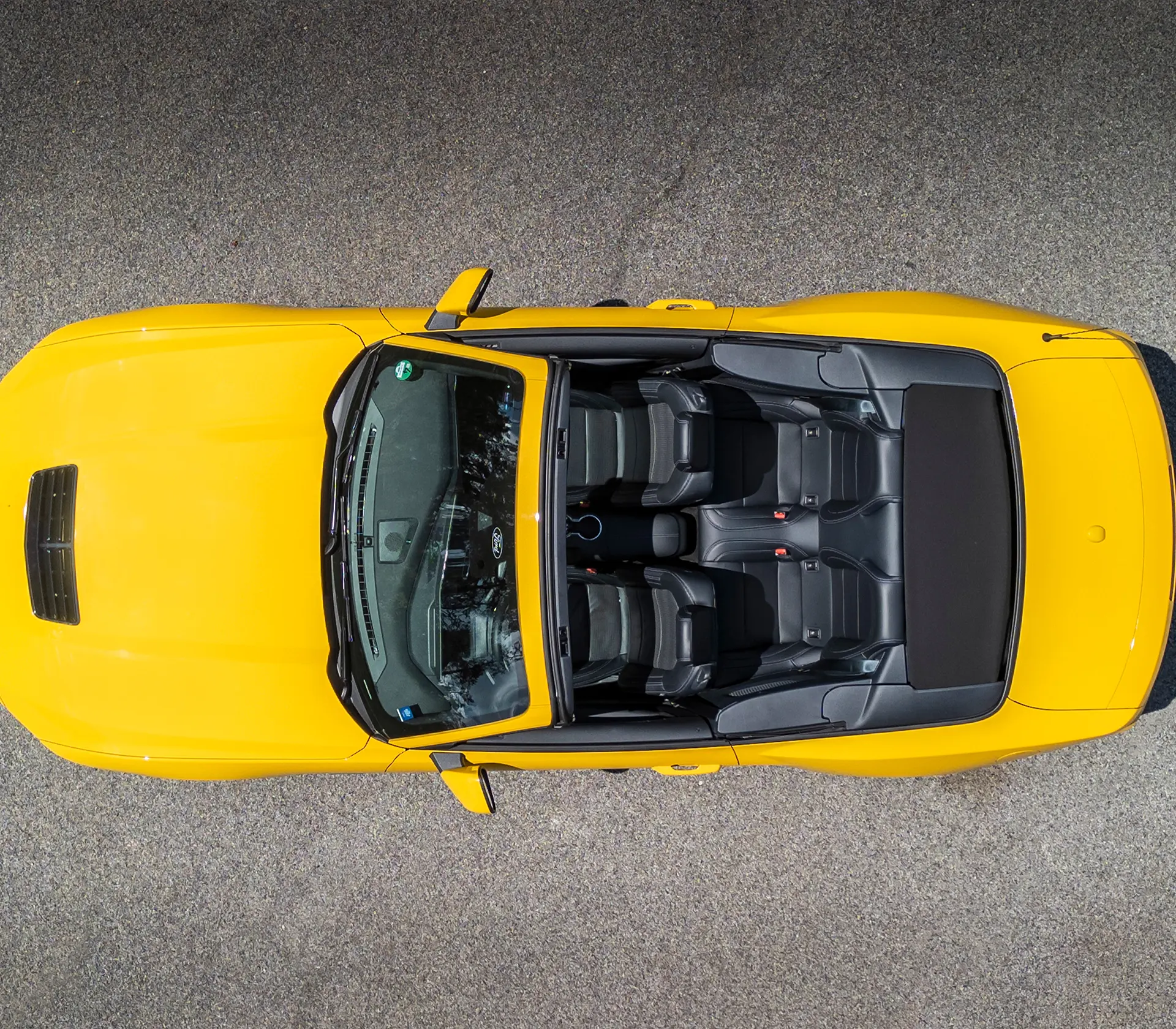 Aufnahme von oben aus der Vogelperspektive auf den gelben Mustang mit geöffnetem Cabrio Dach mit Blick auf die Sitze