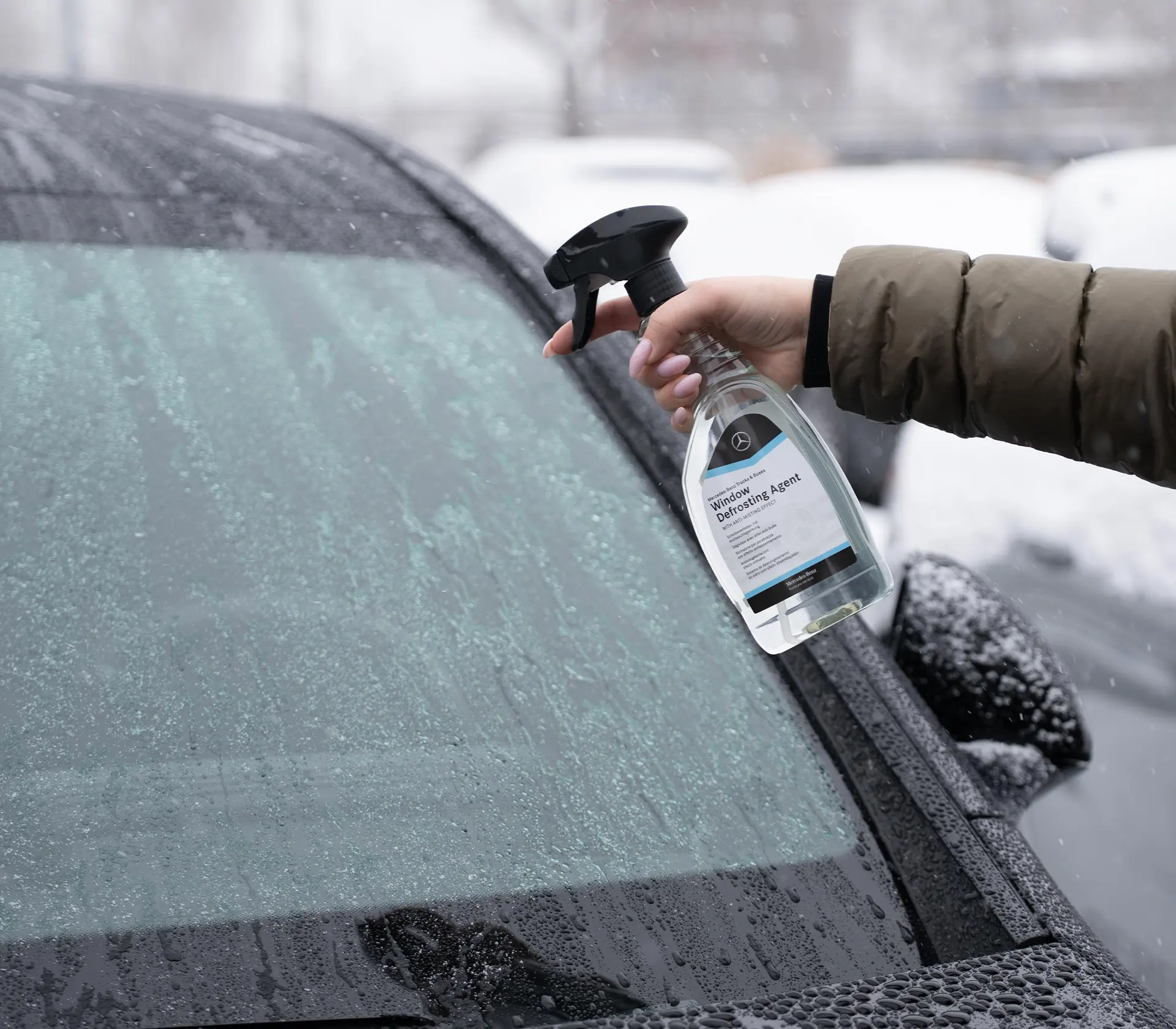 Gefrorene Scheibe wir mit einem Enteiser besprüht