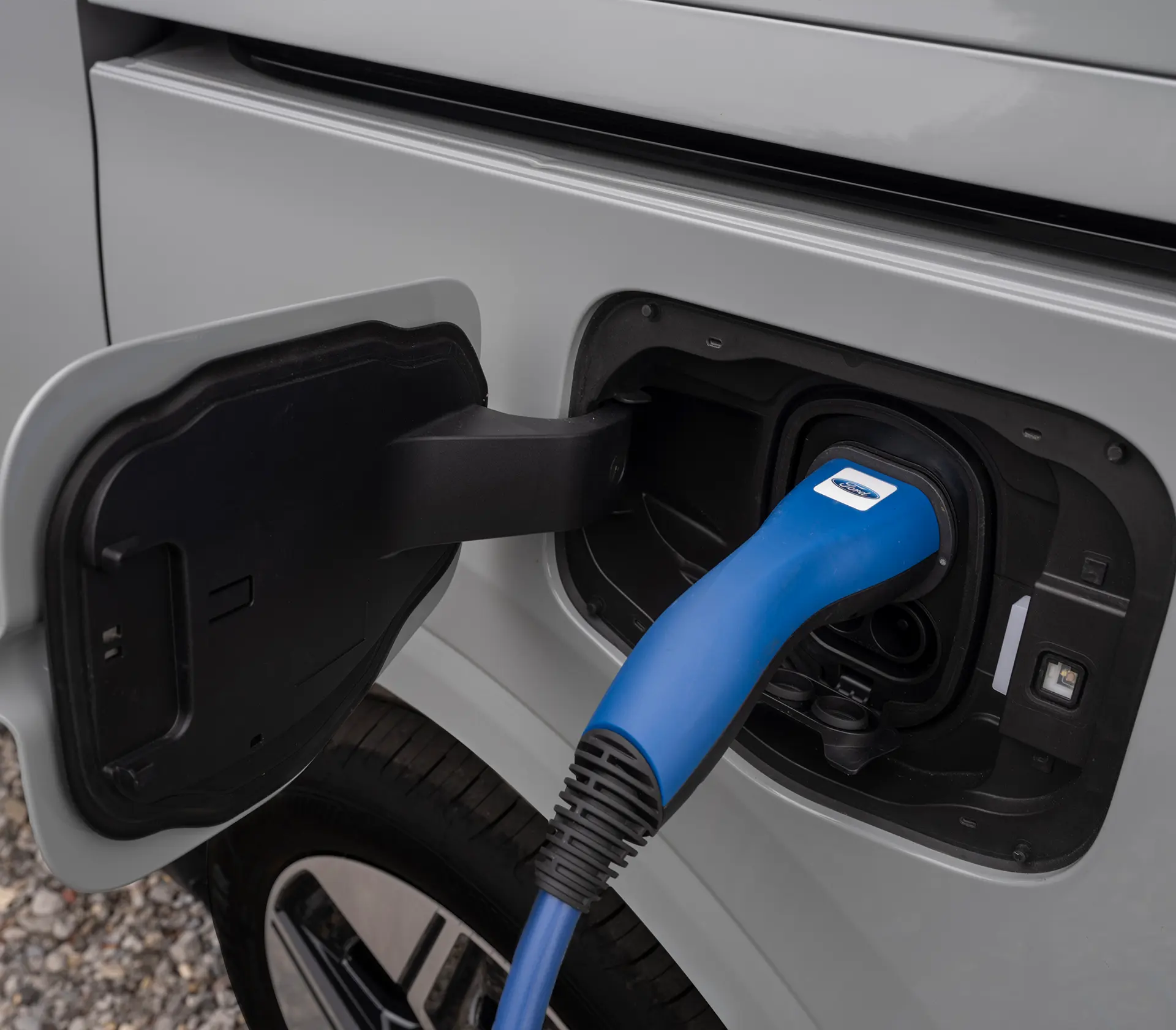 Nahaufnahme von der Ladeklappe des E-Tourneo Courier wie es mit einem Kabel geladen wird