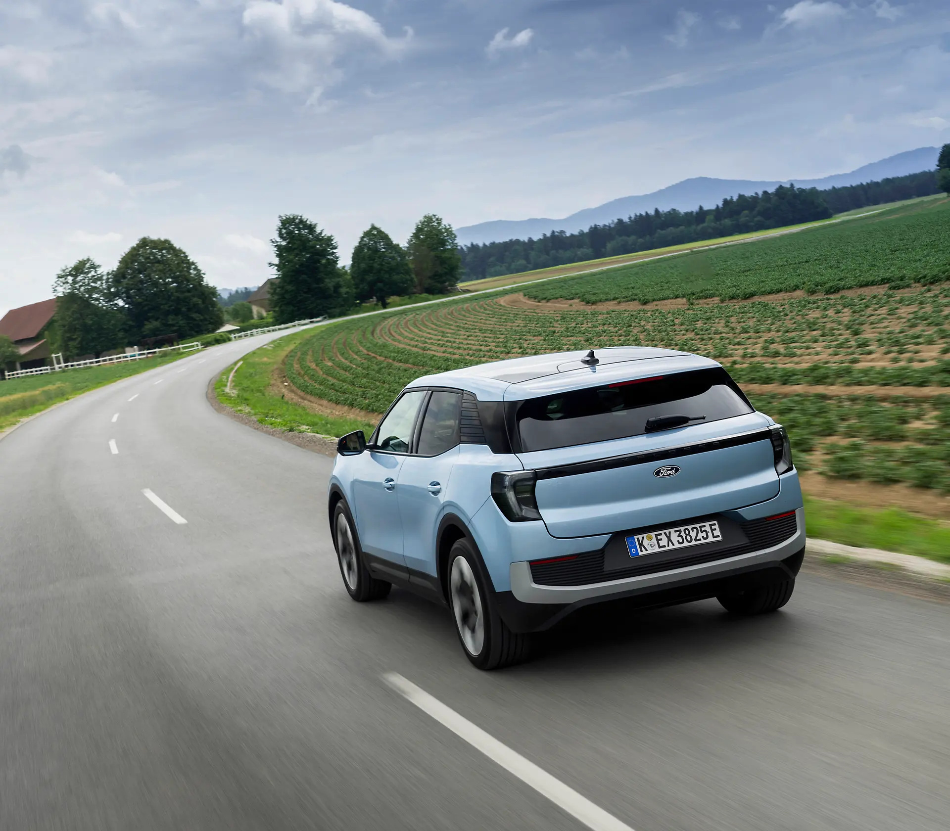 hellblauer Ford Explorer fährt mit Heckansicht auf einer Landstraße