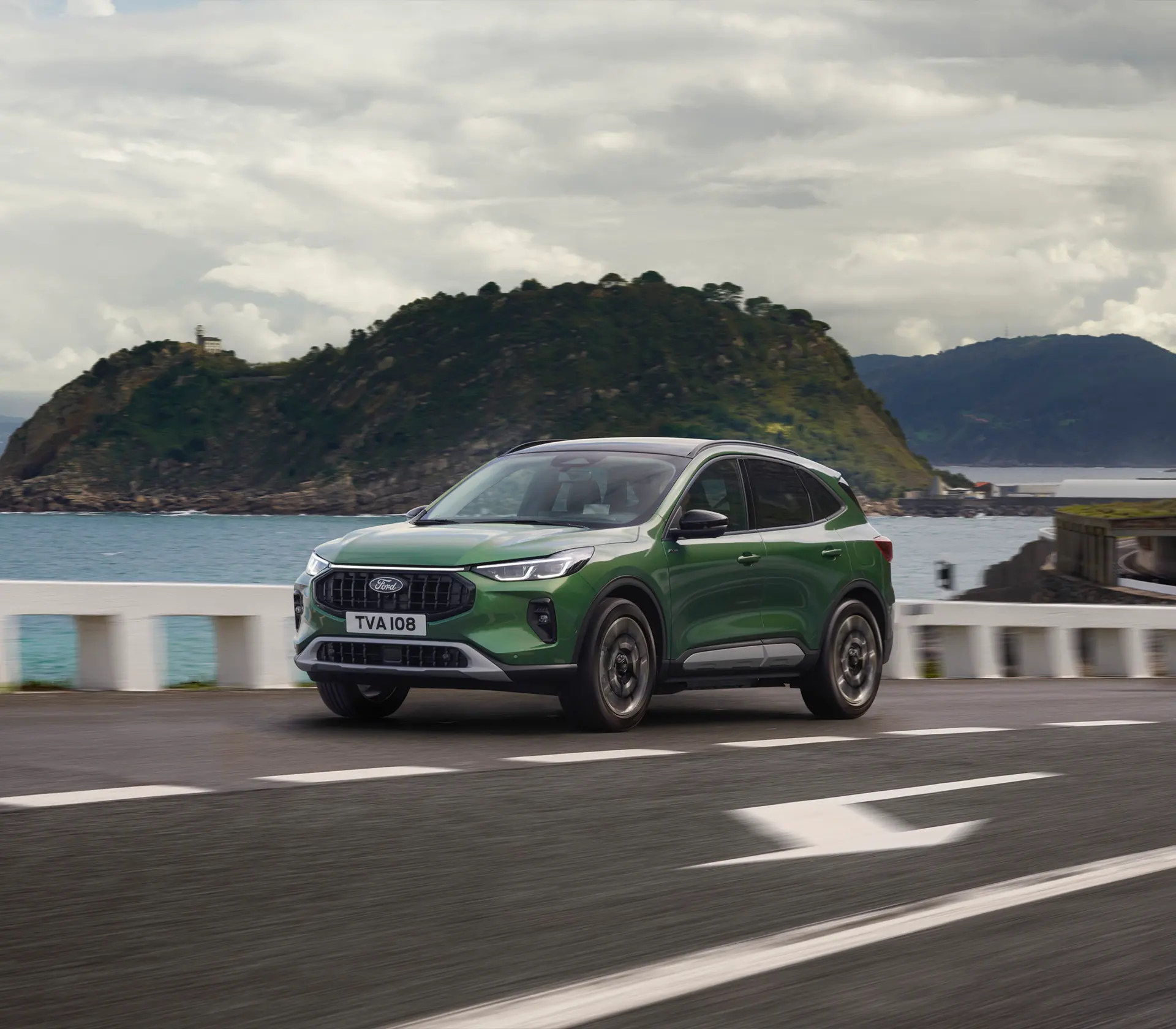 grüner Kuga fährt auf der Straße neben dem Meer