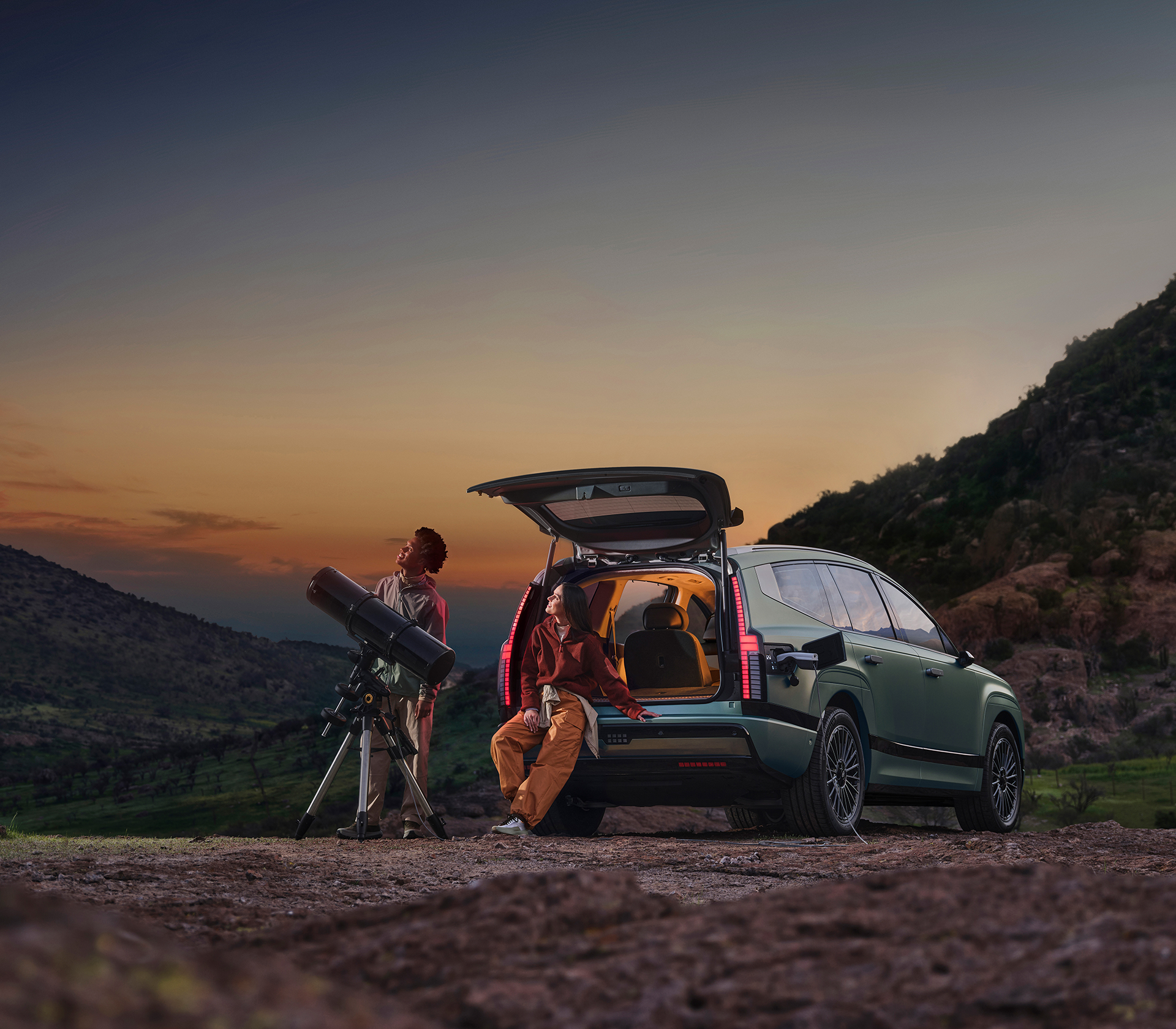 Hyundai IONIQ 9 Heckansicht zwie Personen schauen aus dem Kofferaum mit Fernglas in die Sterne