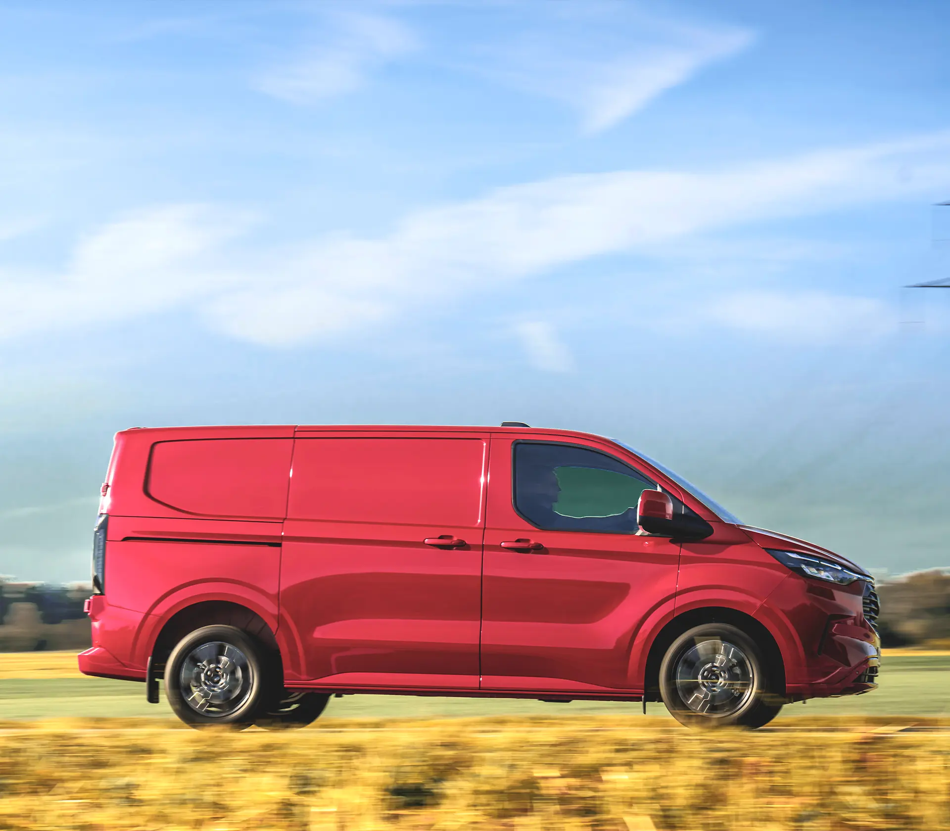 seitliche Ansicht auf roten Transit-Custom, der auf der Landstraße fährt