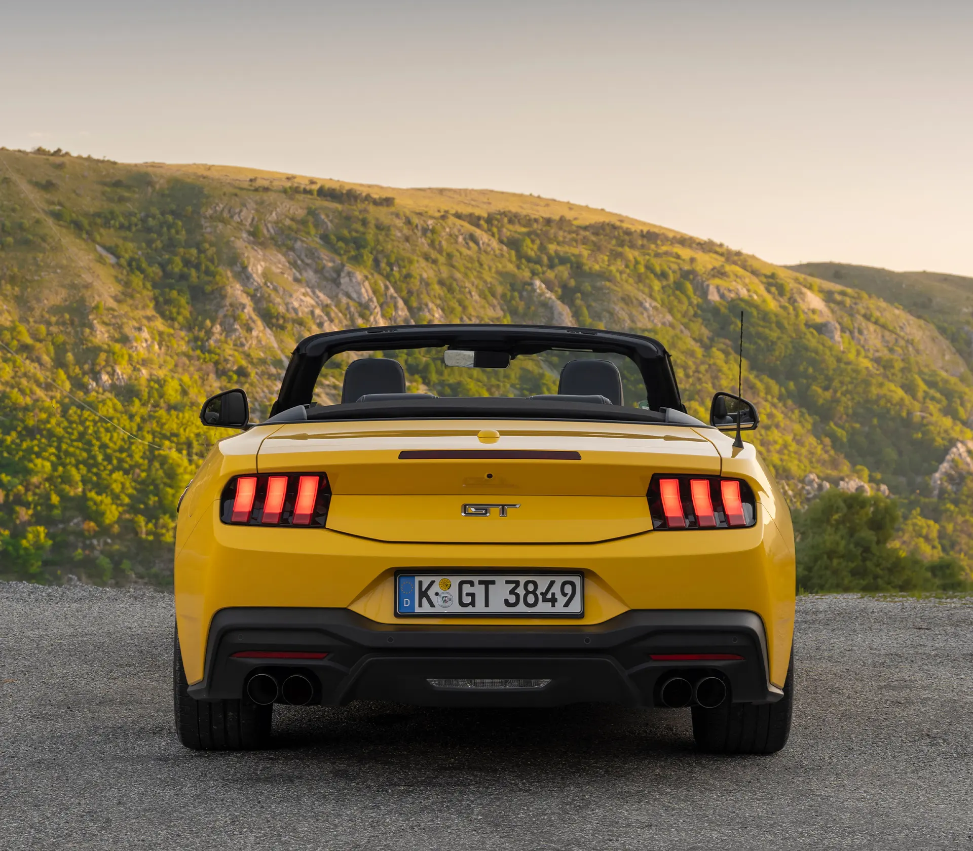 Heckansicht auf gelben Ford Mustang mit bergen im Hintergrund