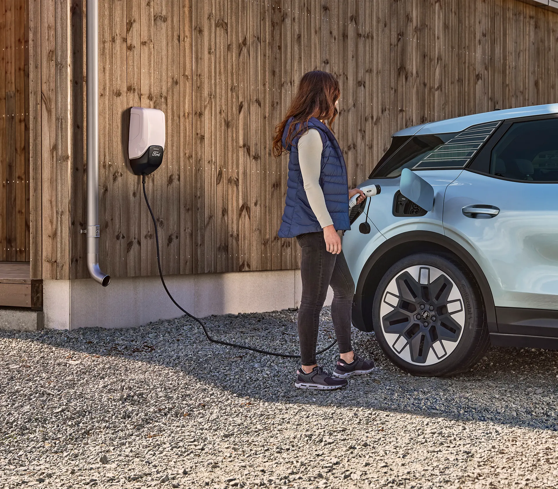 frau will hellblauen Explorer mithilfe einer Wallbox laden