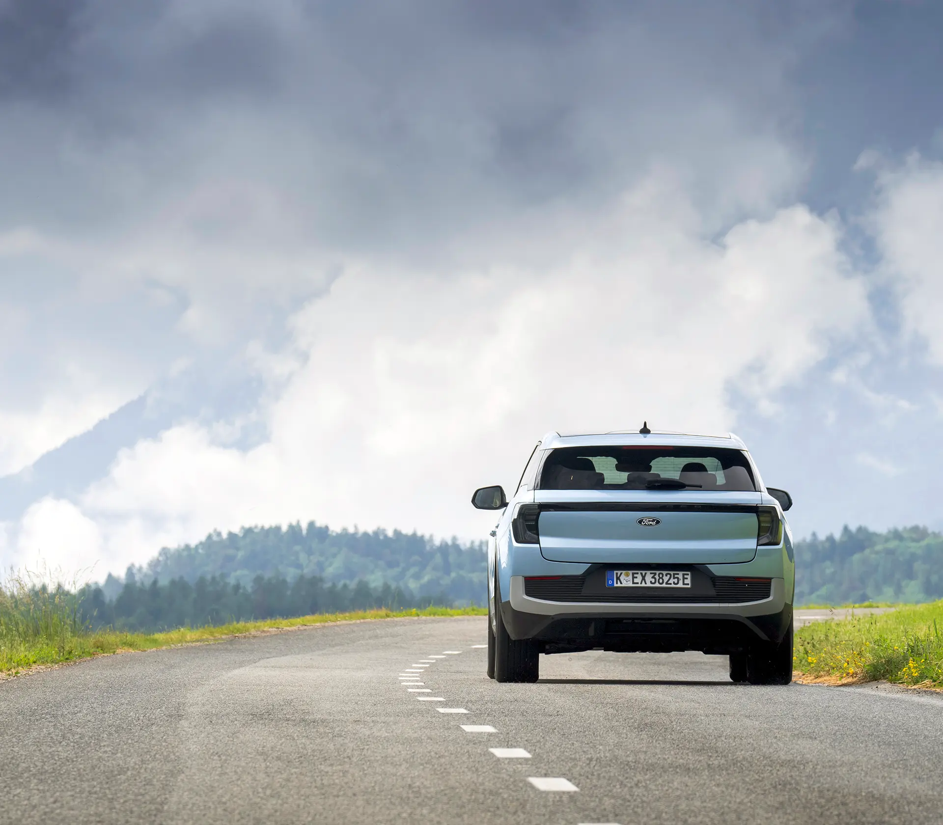 hellblauer Ford Explorer fährt mit Heckansicht auf einer Landstraße