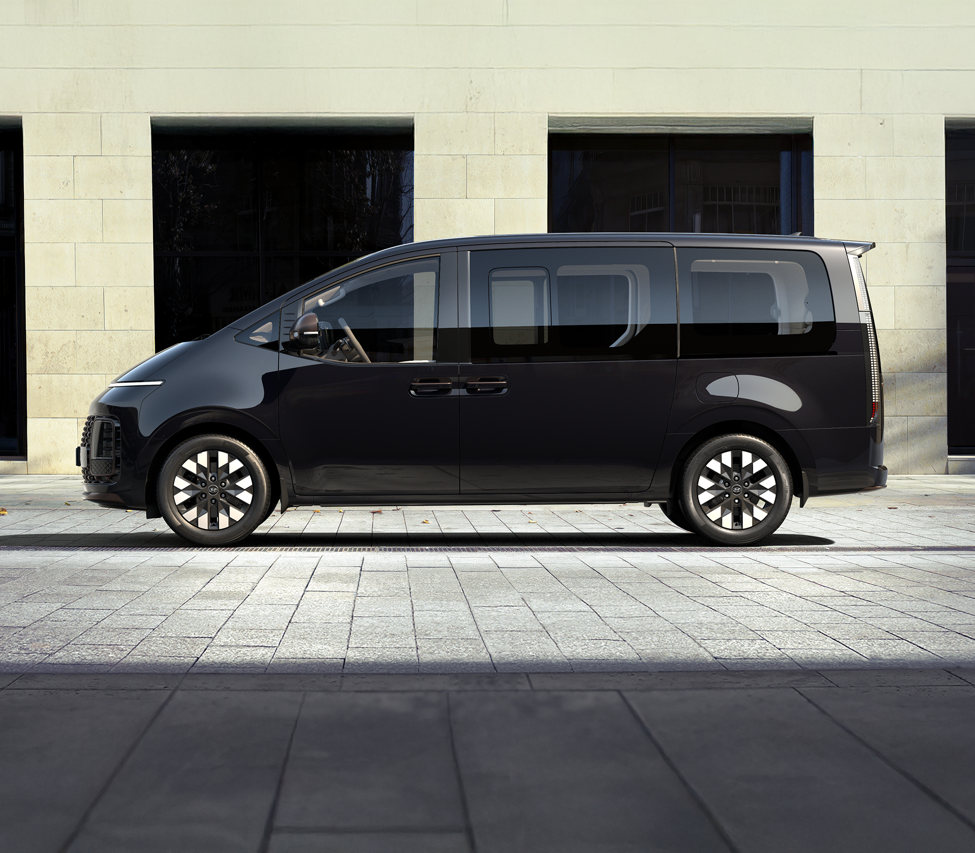 Hyundai Staria in schwarz von der Seite mit einem modernen Hintergrund