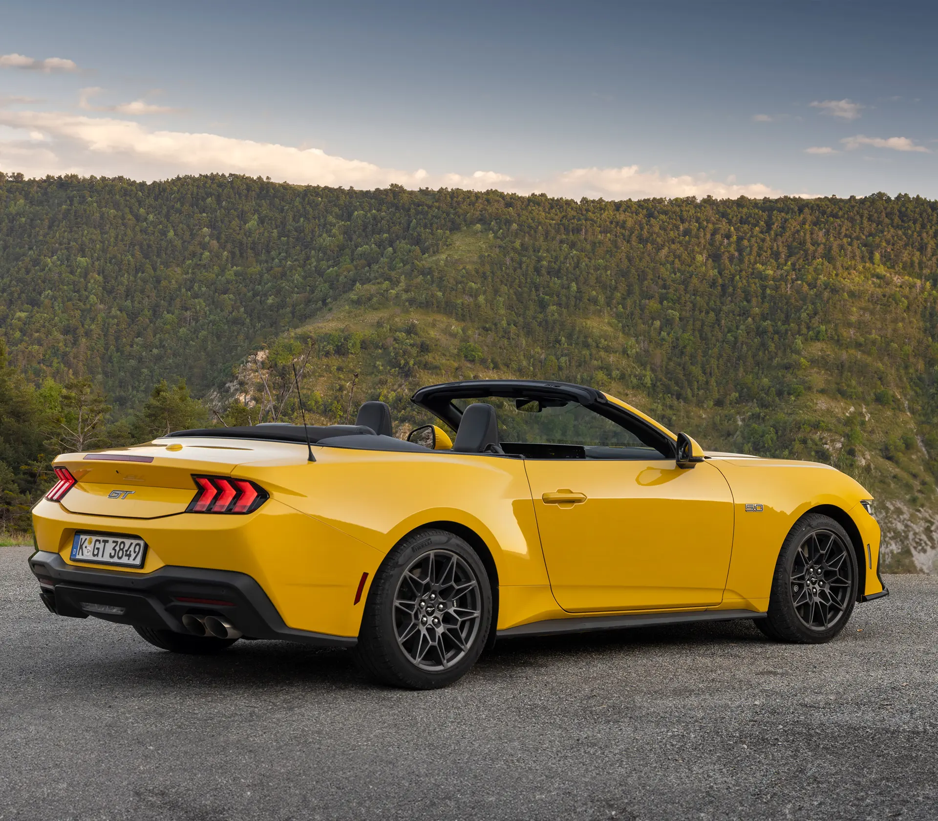 seitliche Heckansicht auf gelben Ford Mustang mit bergen im Hintergrund