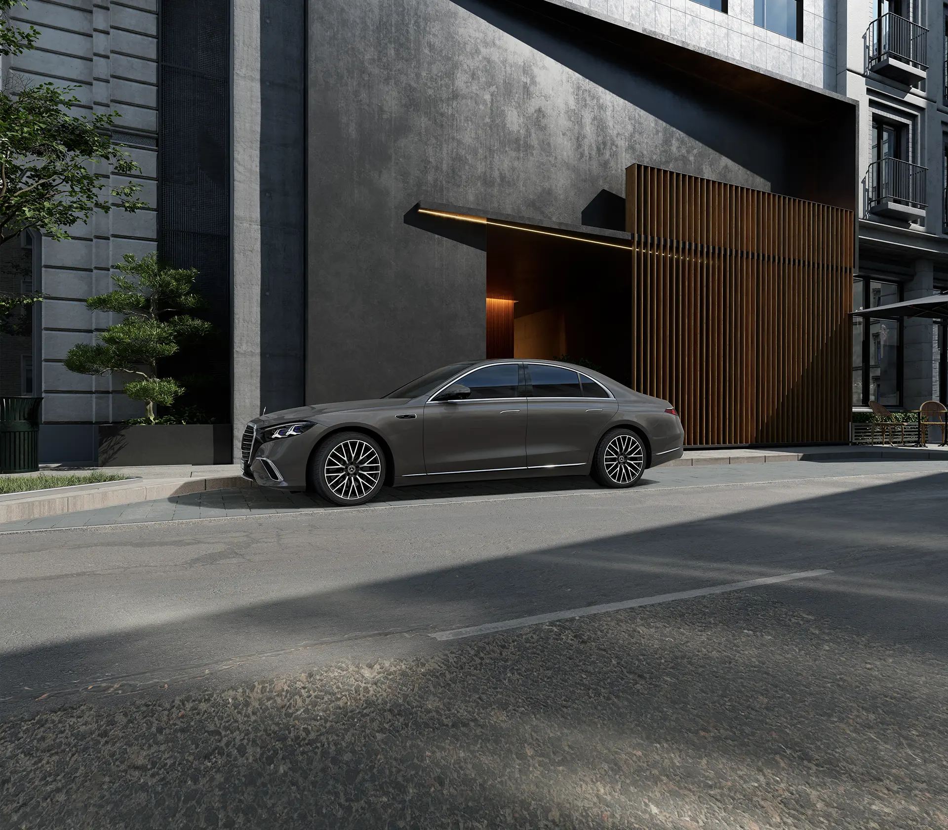die Neue S-Klasse in grau steht seitlich vor einem schwarzen Gebäude geparkt