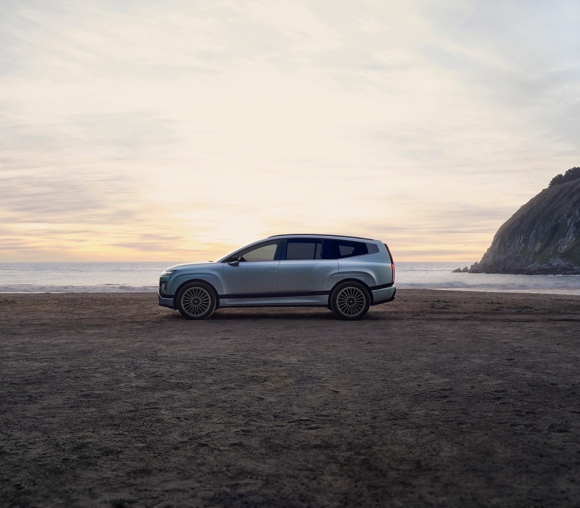 Hyundai IONIQ 9 von der Seite an einem Strand mit dem Meer im Hintergrund